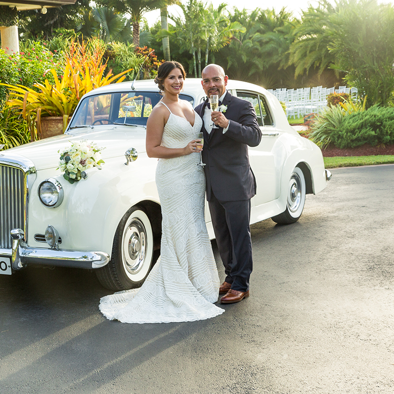 Just married! Bride and groom toast with champagne beside a vintage Rolls-Royce at Longan’s Place.