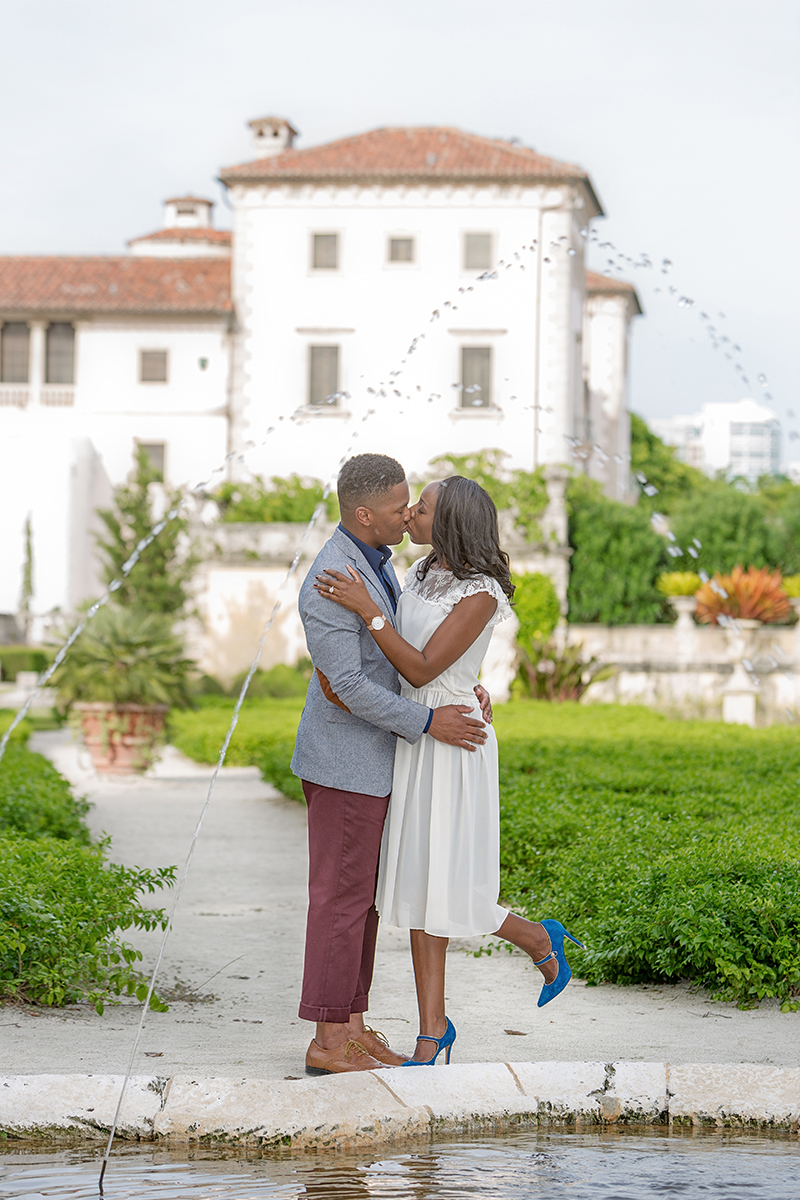 Bride and groom share a dreamy kiss in this engagement photo by the water spout at Vizcaya Museum, Miami.